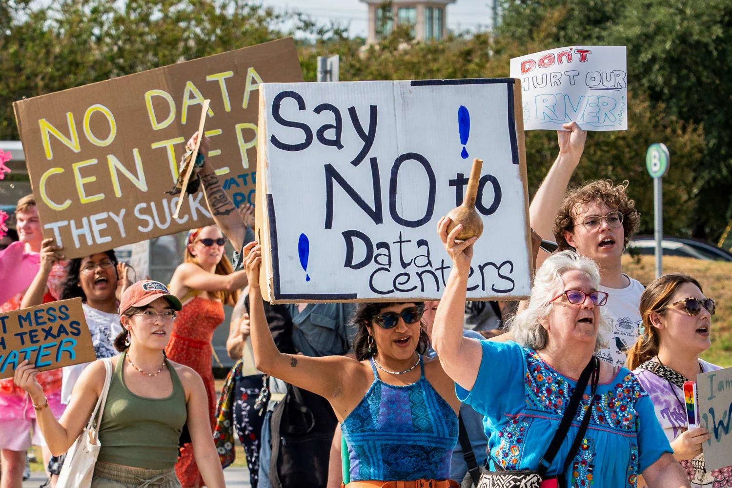 Residents marching with hand-lettered signs reading "Say NO to Data Centers"